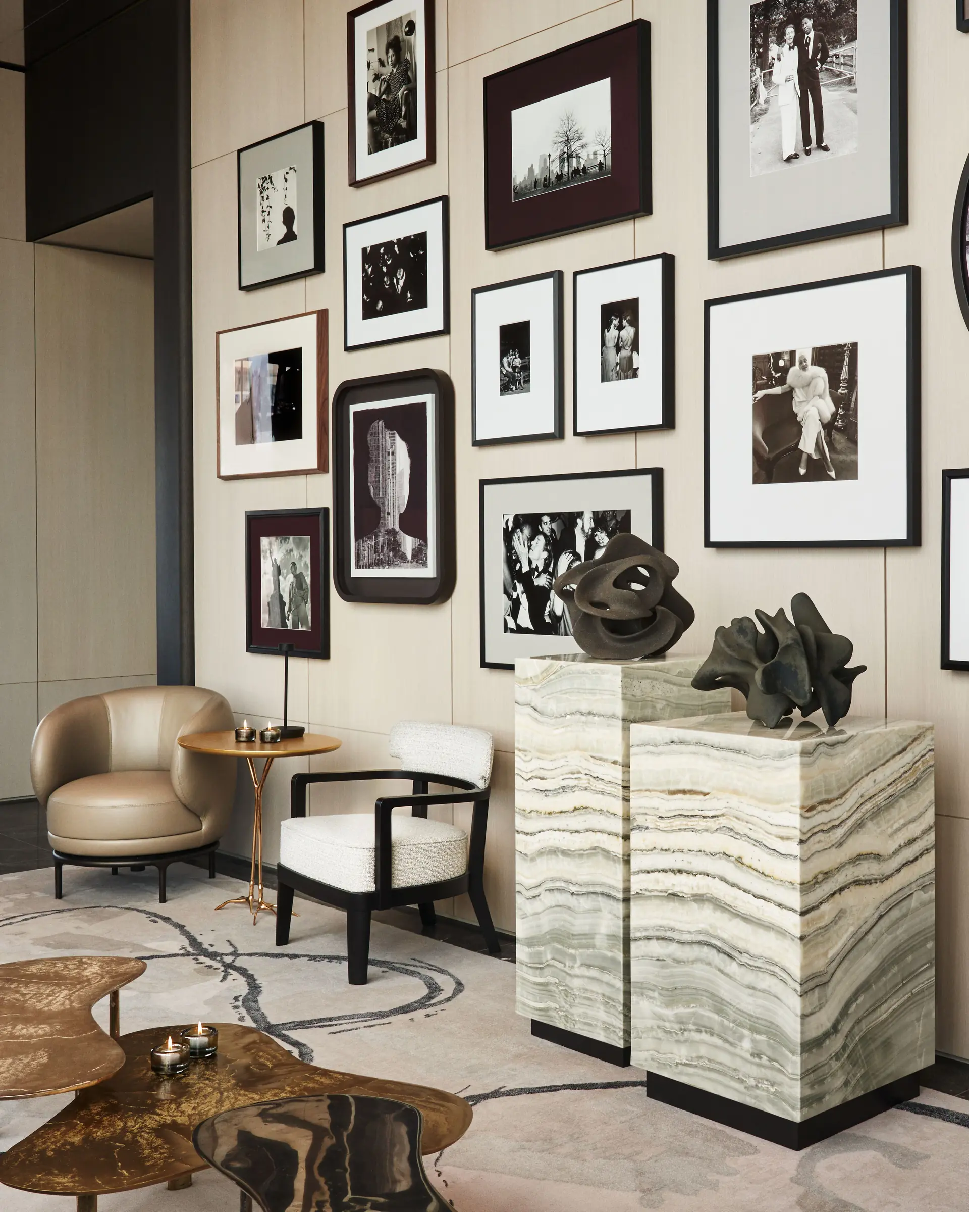 Lounge with a black-and-white photo gallery wall, onyx pedestals with bronze sculptures and leather armchair, for Centurion New York.