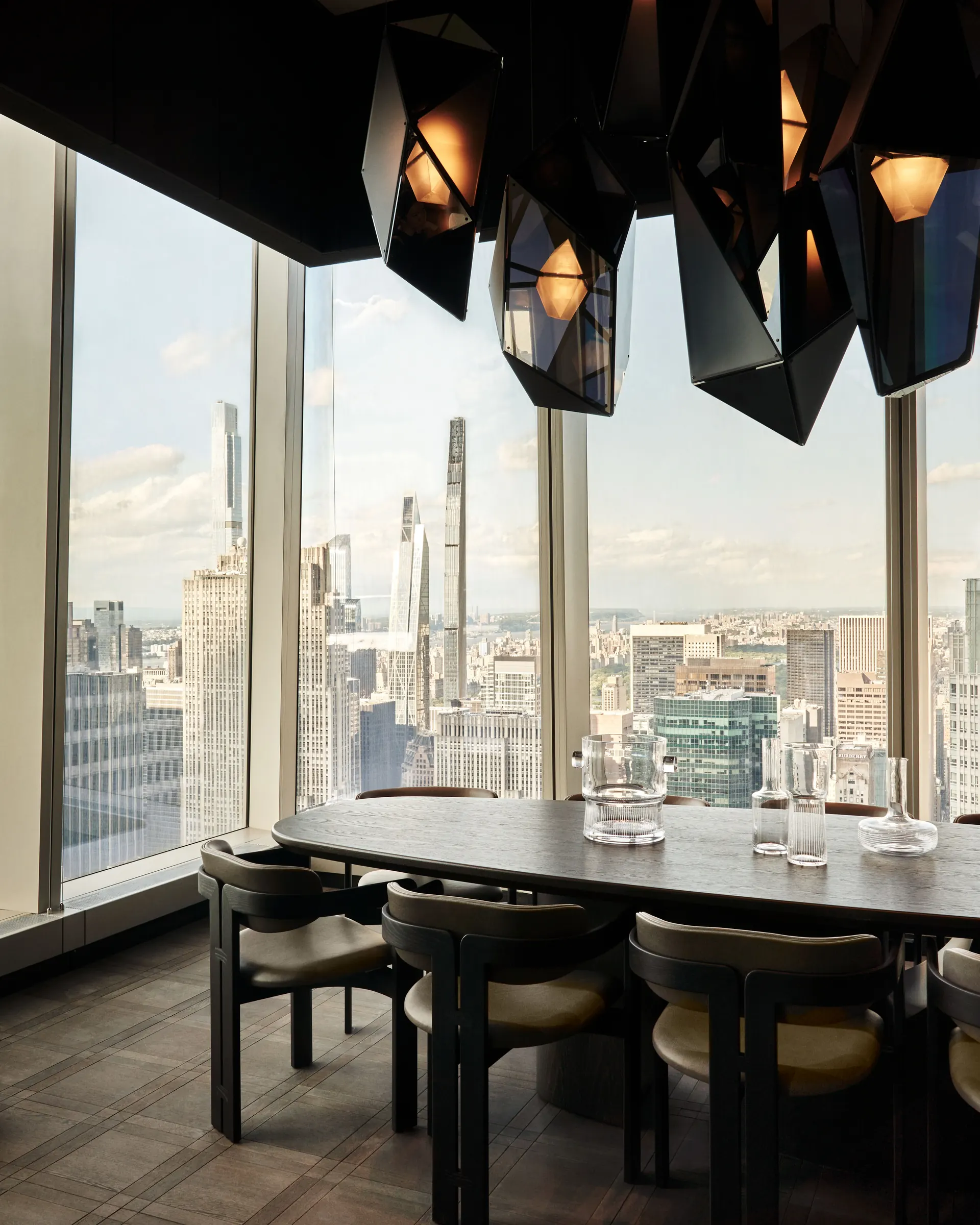 Private dining room with oval table, faceted pendant lights and floor-to-ceiling Manhattan skyline views, for Centurion New York.