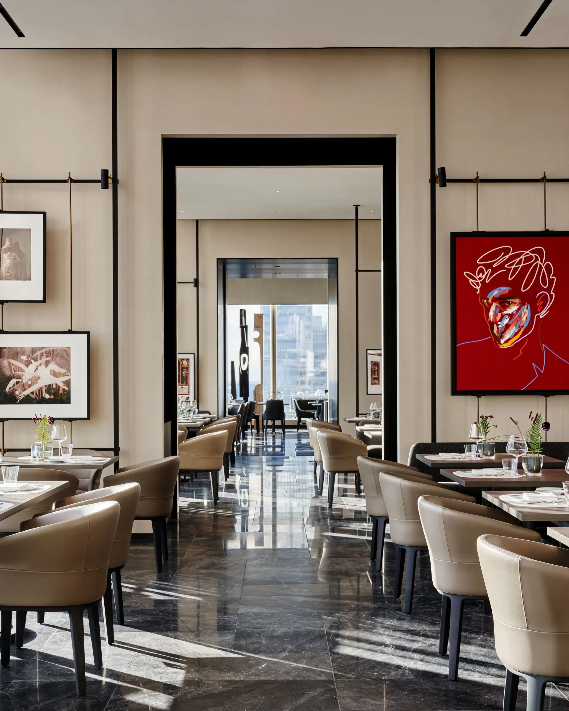Restaurant dining room with beige leather chairs, dark marble floor and red portrait artwork, for Centurion New York.