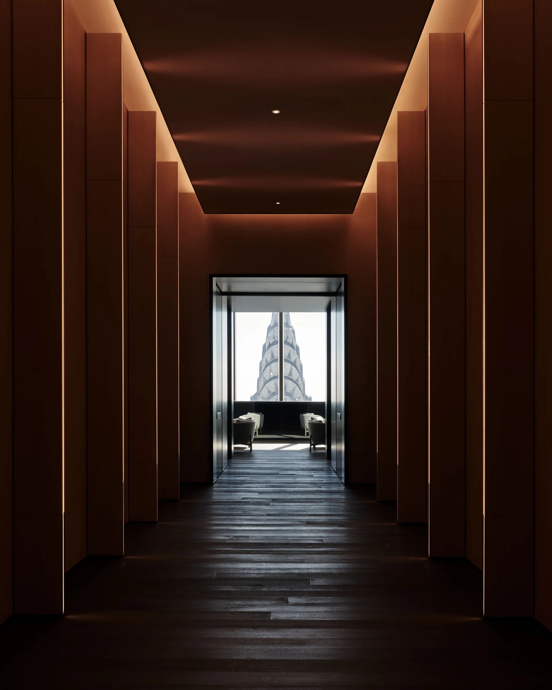Dim wood-paneled corridor with lit vertical panels leading to a lounge framing the Chrysler Building spire, for Centurion New York.