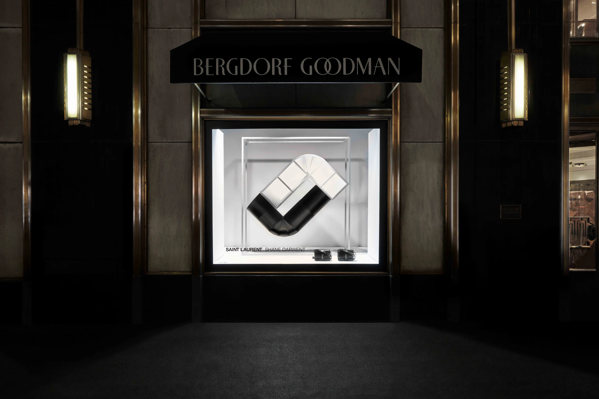 Night view of a Bergdorf Goodman store window with a black and white sculptural installation and shoes, for Saint Laurent.