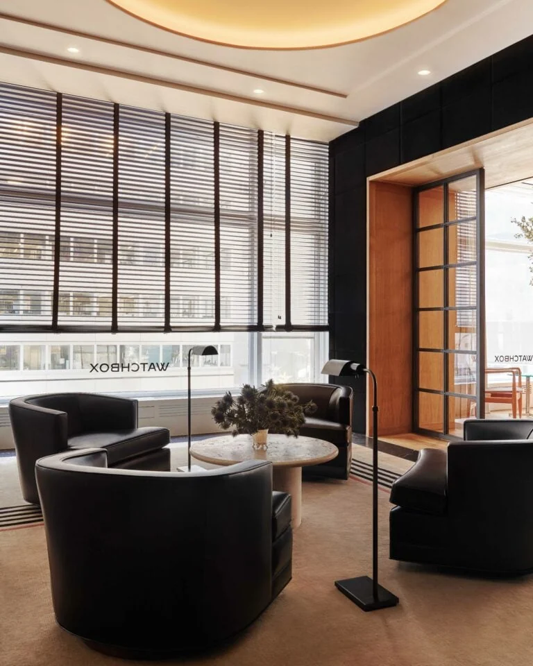Interior lounge with black leather swivel armchairs, terrazzo table and tall window blinds, for WatchBox.