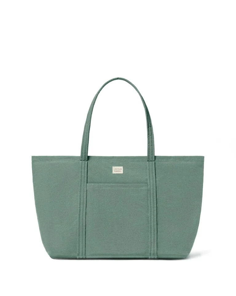Sage green canvas tote bag with front pocket and cream logo label on a white background, for Loeffler Randall.