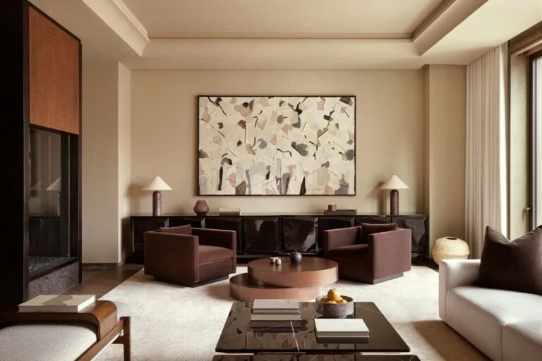 Living room with brown armchairs, abstract artwork, dark marble coffee table and cream sofa, for Aman.